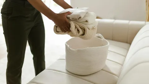 White linens being placed into a real laundry basket
