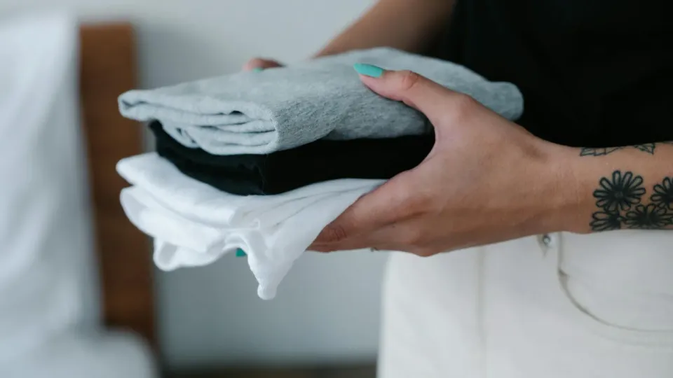 Hands holding a finished stack of folded laundry