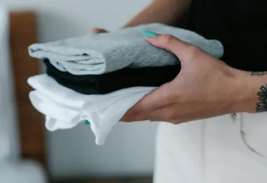 Hands holding a finished stack of folded laundry