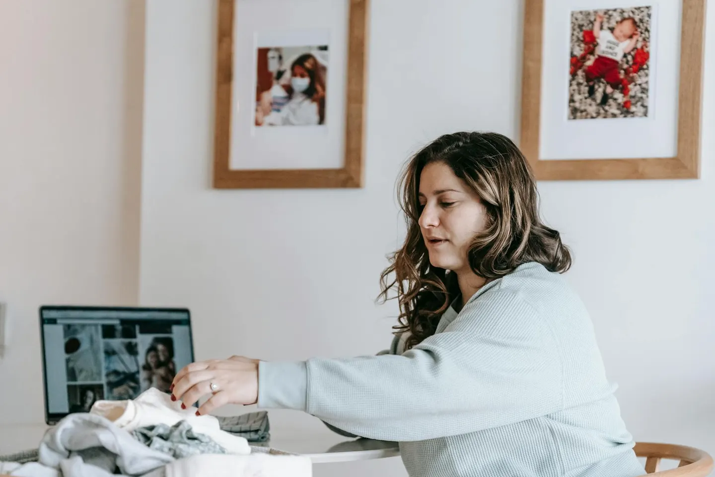A person folding laundry beside a laptop at a table