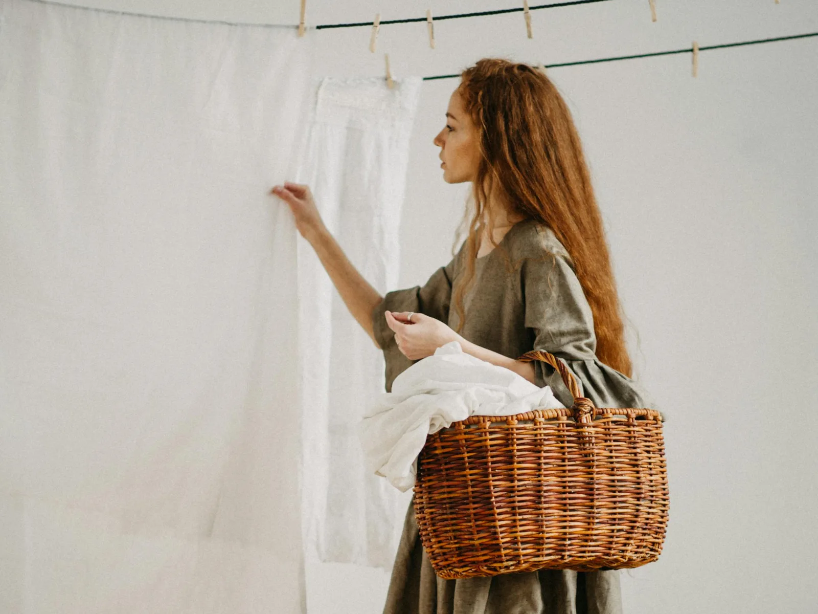 A real person handling white laundry beside a wicker basket