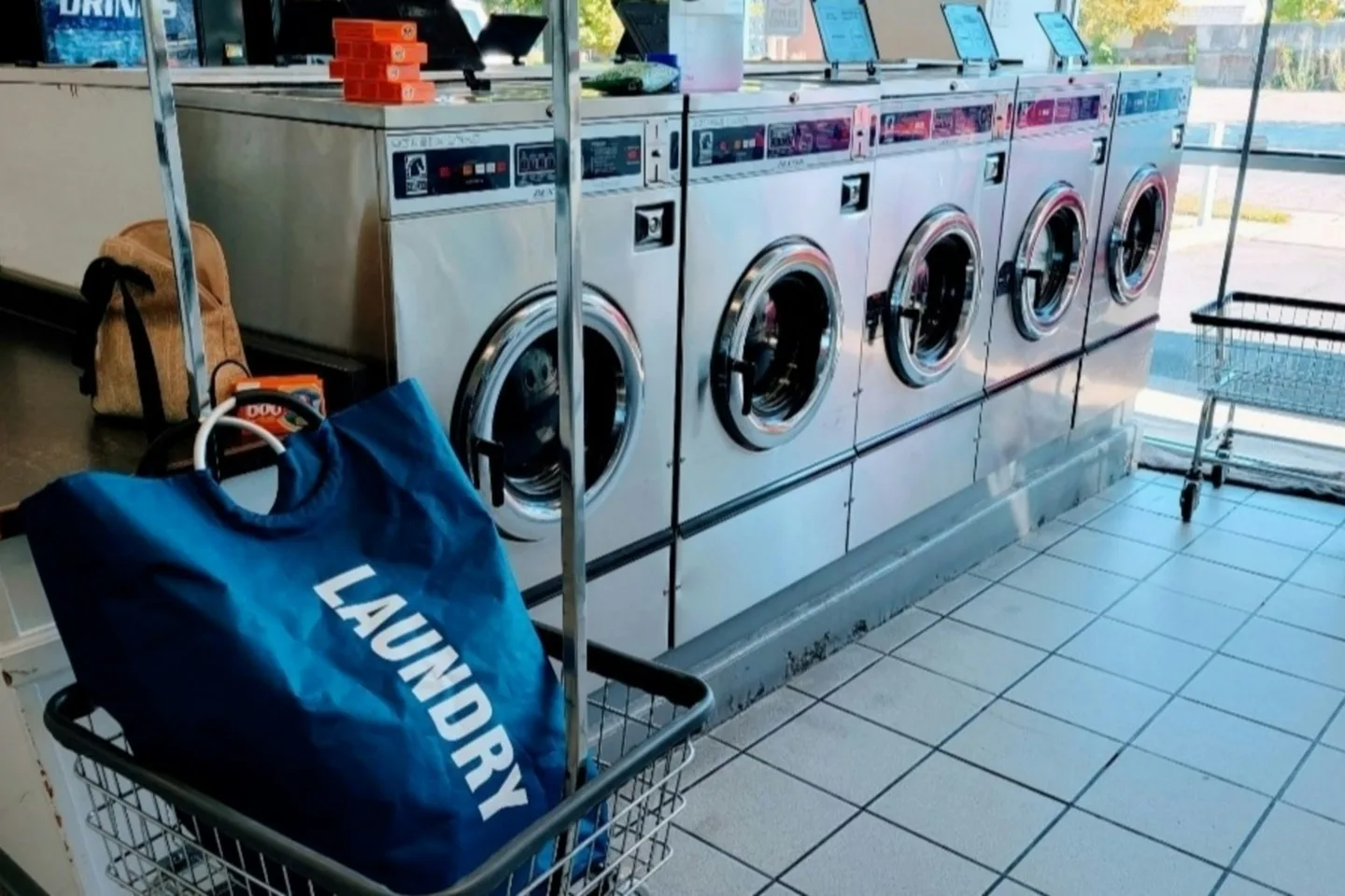 A canvas laundry bag beside a workroom washer before a handling review