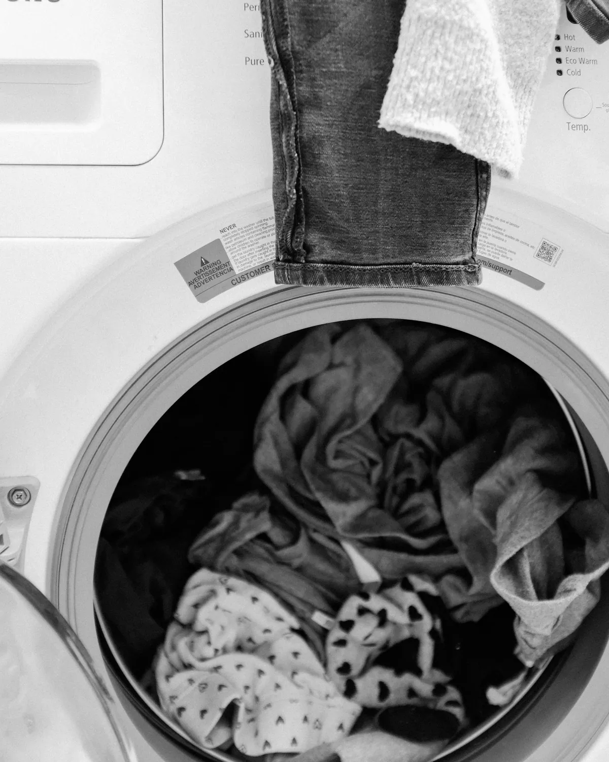 White textiles tumbling inside a clean front-load washer drum.