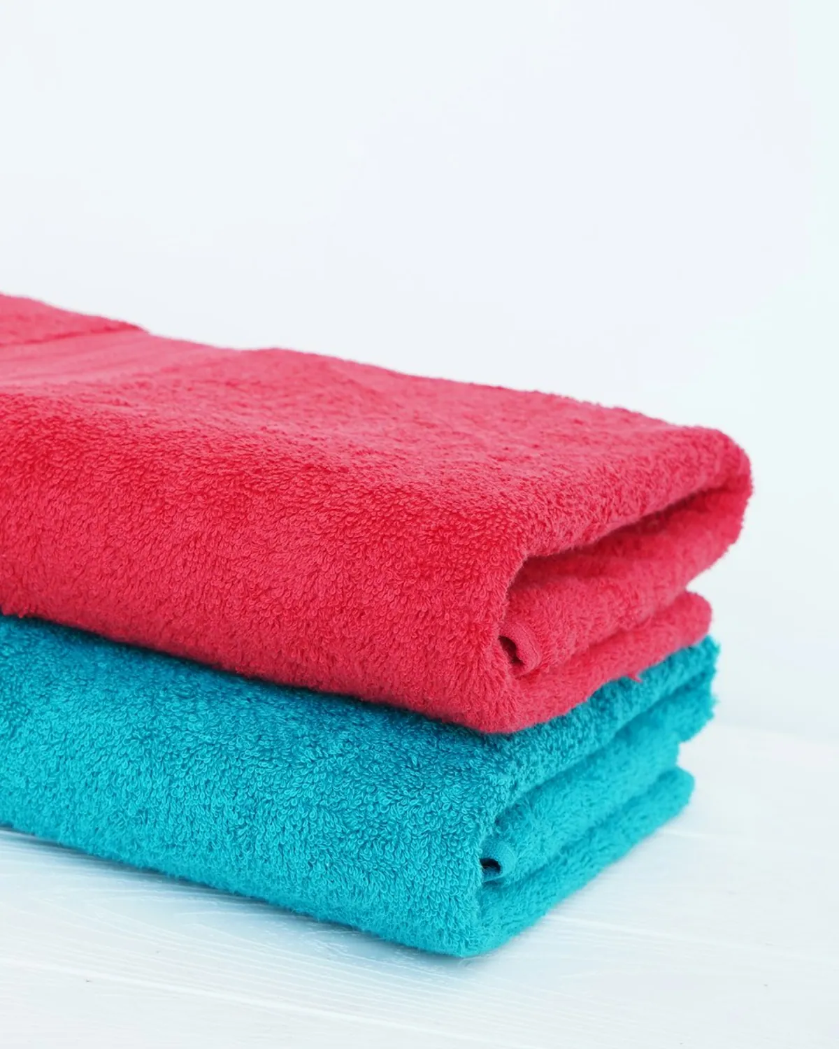 A neat stack of folded clean white towels on a residential surface.