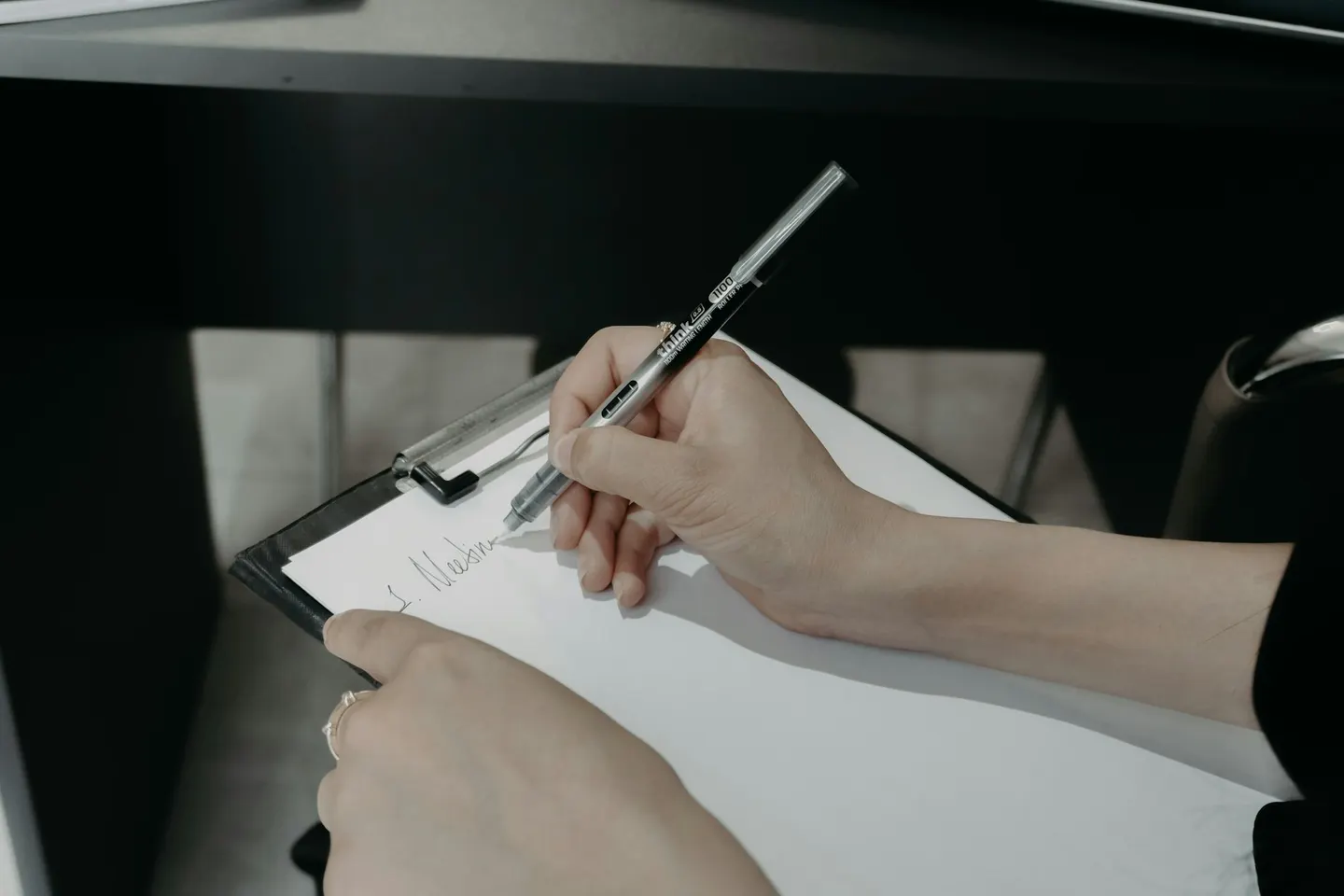 A person writing on a clipboard beside service agreement notes
